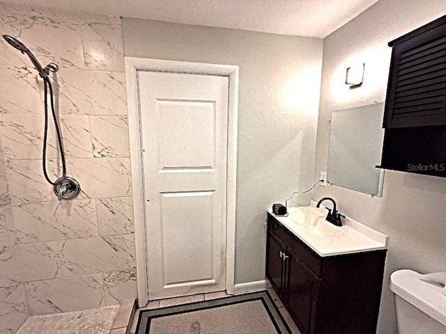 bathroom featuring vanity, a tile shower, and toilet