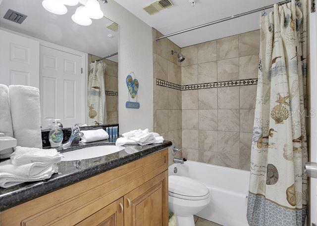 full bathroom featuring vanity, shower / bath combination with curtain, and toilet