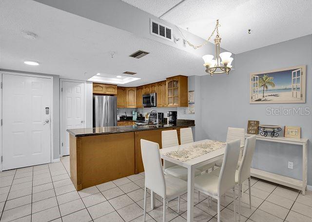 kitchen with appliances with stainless steel finishes, a textured ceiling, decorative light fixtures, kitchen peninsula, and a chandelier