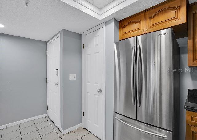 kitchen with stainless steel fridge, a textured ceiling, and light tile patterned flooring