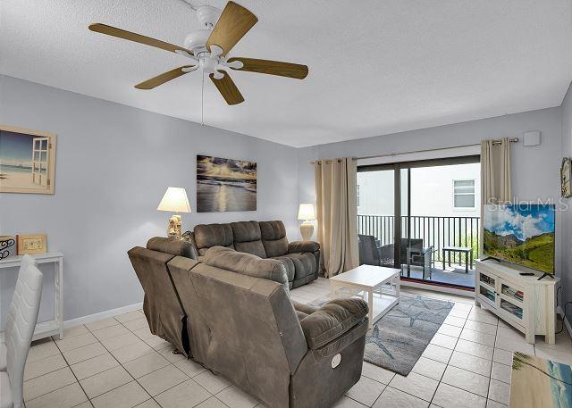 living room featuring light tile patterned flooring, ceiling fan, and a textured ceiling