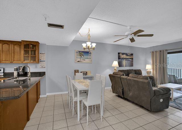 tiled dining room with ceiling fan, sink, and a textured ceiling