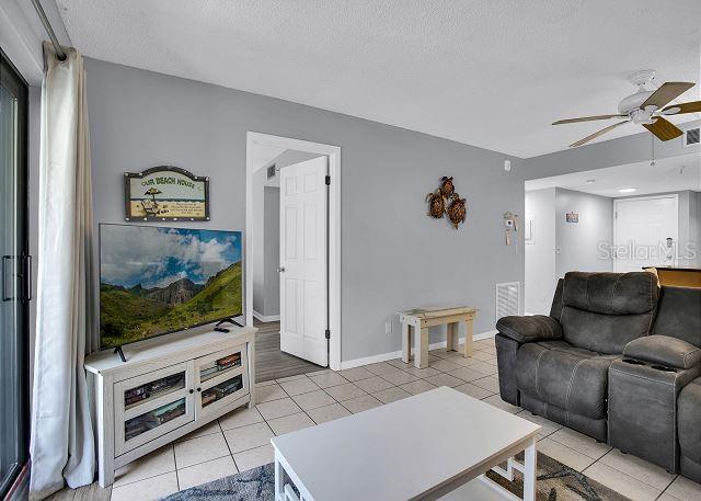 tiled living room featuring ceiling fan and a textured ceiling