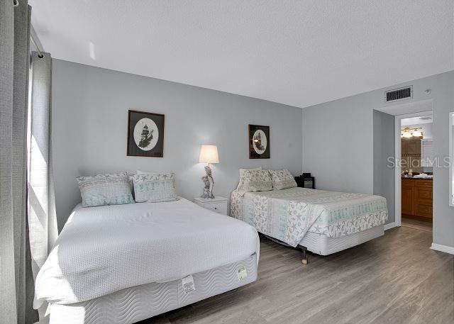 bedroom with dark wood-type flooring, a textured ceiling, and ensuite bath