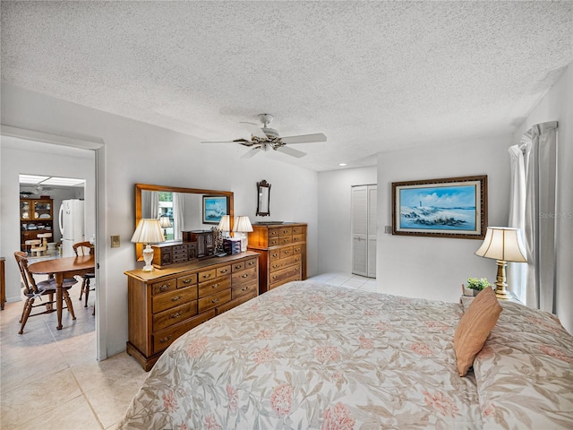 tiled bedroom with a textured ceiling, ceiling fan, and a closet