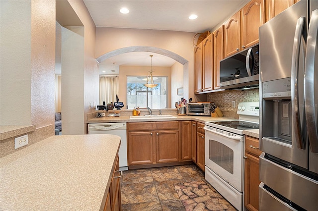 kitchen with tasteful backsplash, hanging light fixtures, sink, and appliances with stainless steel finishes