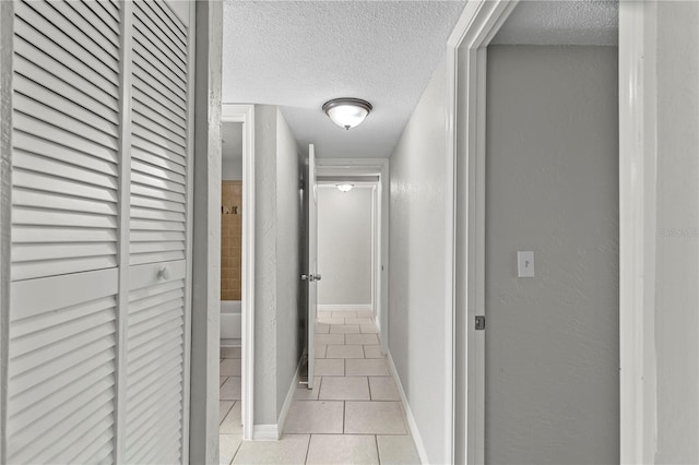 corridor with light tile patterned flooring and a textured ceiling