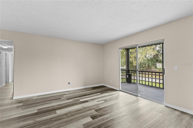 unfurnished room with wood-type flooring and a textured ceiling