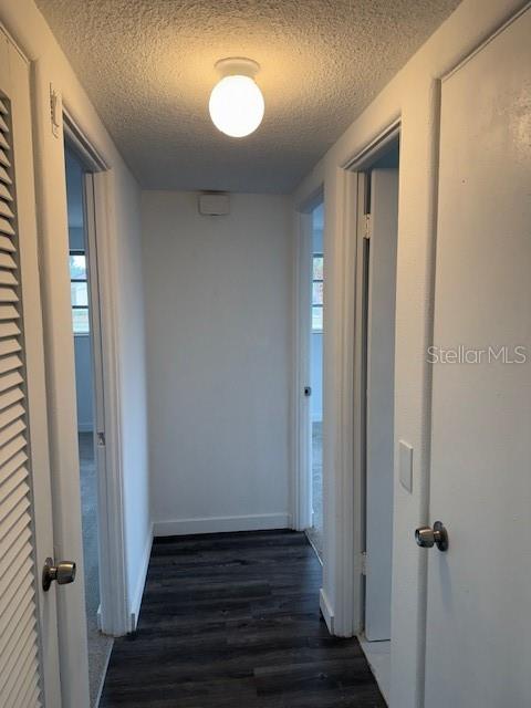 corridor with dark hardwood / wood-style floors and a textured ceiling