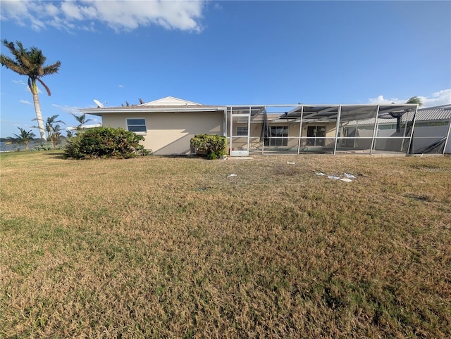 back of property featuring a yard and glass enclosure