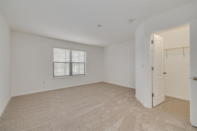 unfurnished bedroom featuring light carpet, a closet, and a spacious closet