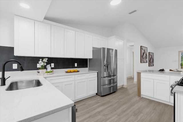 kitchen featuring stainless steel fridge, visible vents, black gas stove, white cabinetry, and a sink