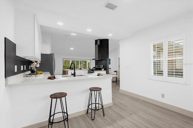 kitchen featuring sink, a breakfast bar, white cabinetry, stainless steel appliances, and kitchen peninsula