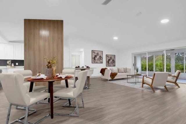 dining area featuring lofted ceiling and light wood-type flooring