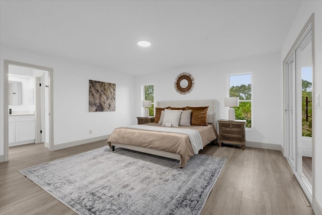 bedroom with connected bathroom and light wood-type flooring