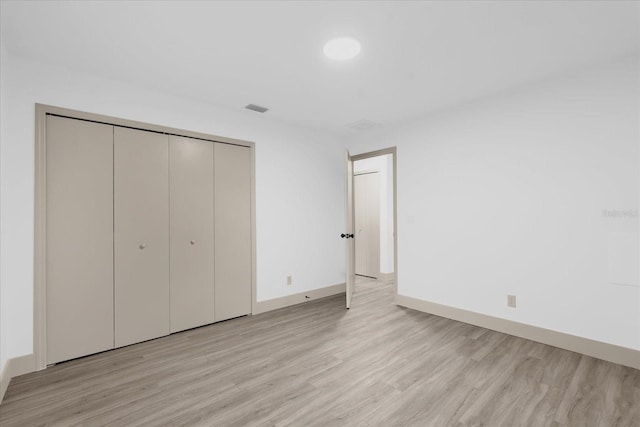 unfurnished bedroom with a closet and light wood-type flooring