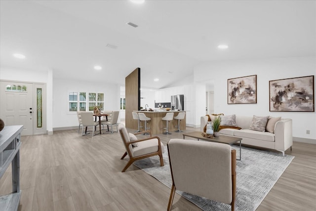 living room featuring lofted ceiling and light hardwood / wood-style flooring