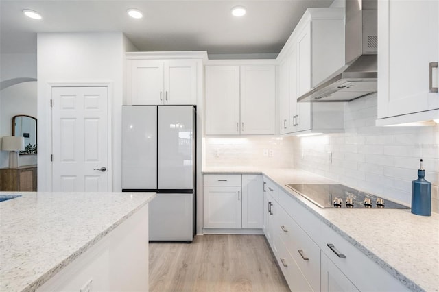 kitchen featuring white refrigerator, white cabinetry, and wall chimney range hood