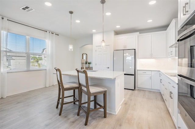 kitchen featuring white cabinets, hanging light fixtures, white fridge, a center island, and stainless steel oven