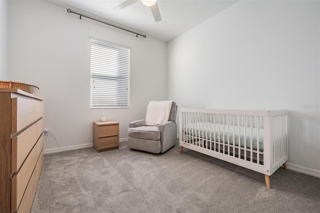 carpeted bedroom featuring a crib and ceiling fan