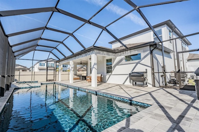 view of pool featuring a patio area, an in ground hot tub, ceiling fan, and glass enclosure