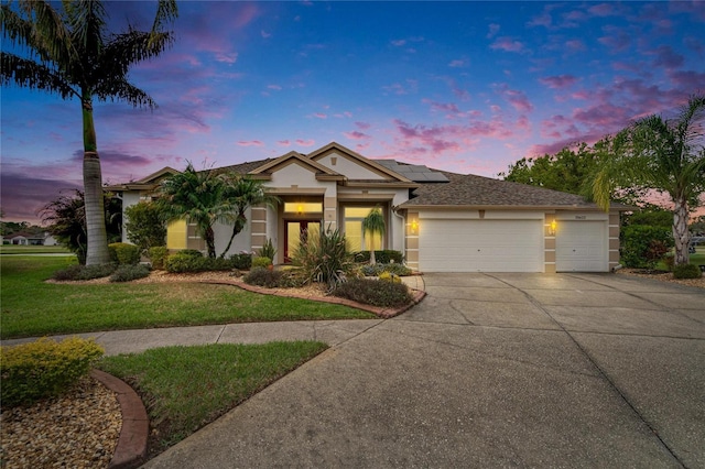 single story home with a garage, concrete driveway, a yard, roof mounted solar panels, and stucco siding