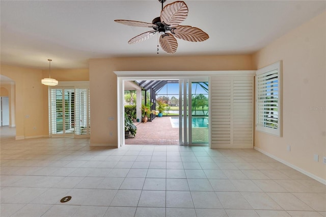 interior space with ceiling fan, baseboards, and light tile patterned floors