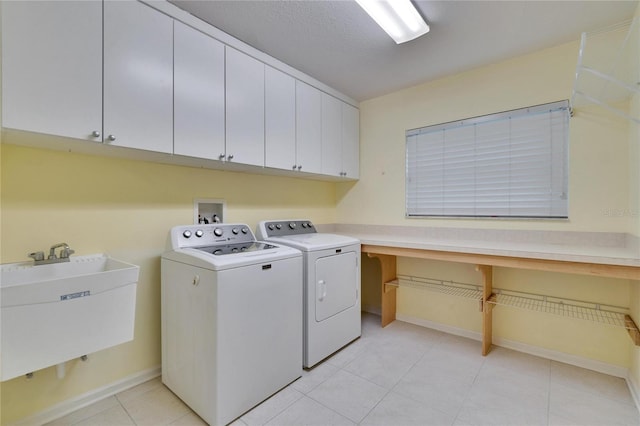 washroom with cabinet space, light tile patterned floors, baseboards, washer and clothes dryer, and a sink