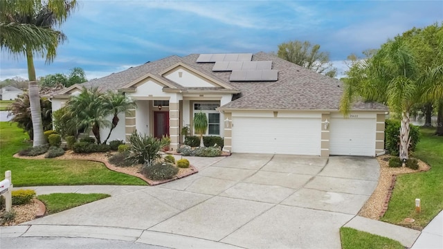 view of front of house featuring roof with shingles, stucco siding, concrete driveway, roof mounted solar panels, and a garage