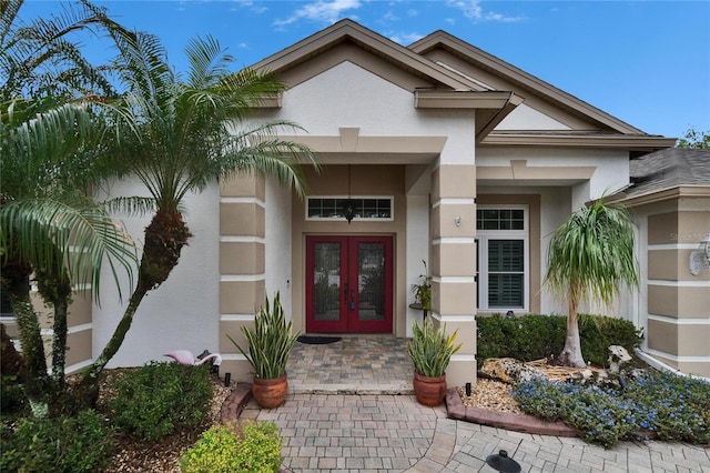 view of exterior entry featuring stucco siding and french doors