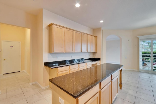 kitchen featuring arched walkways, light tile patterned floors, and light brown cabinetry