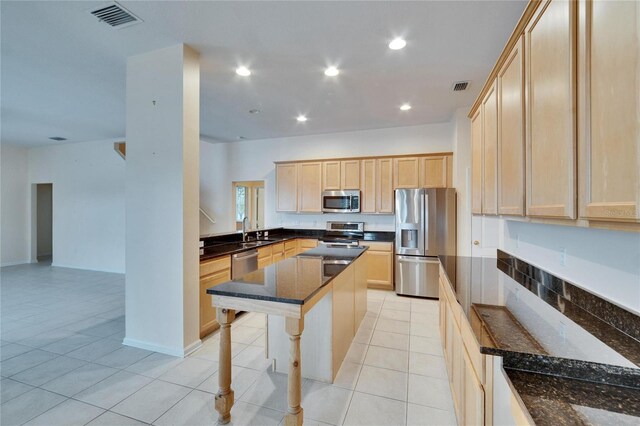 kitchen with visible vents, appliances with stainless steel finishes, dark stone counters, and light brown cabinetry