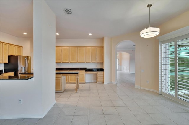 kitchen featuring arched walkways, light brown cabinets, visible vents, dark countertops, and stainless steel fridge