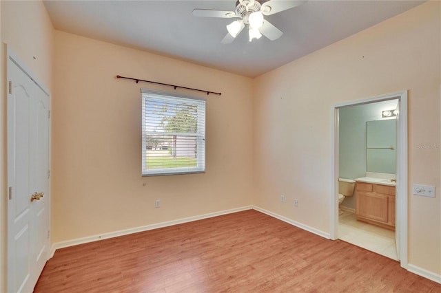 unfurnished bedroom featuring light wood-type flooring, connected bathroom, and baseboards