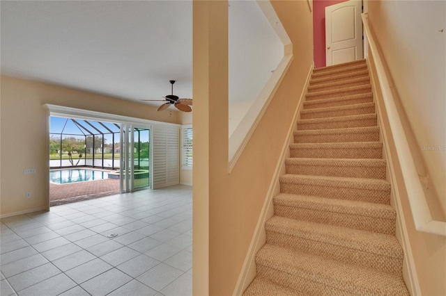 stairs featuring a ceiling fan, tile patterned flooring, a sunroom, and baseboards