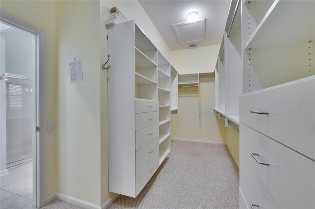 walk in closet featuring attic access, light colored carpet, and visible vents