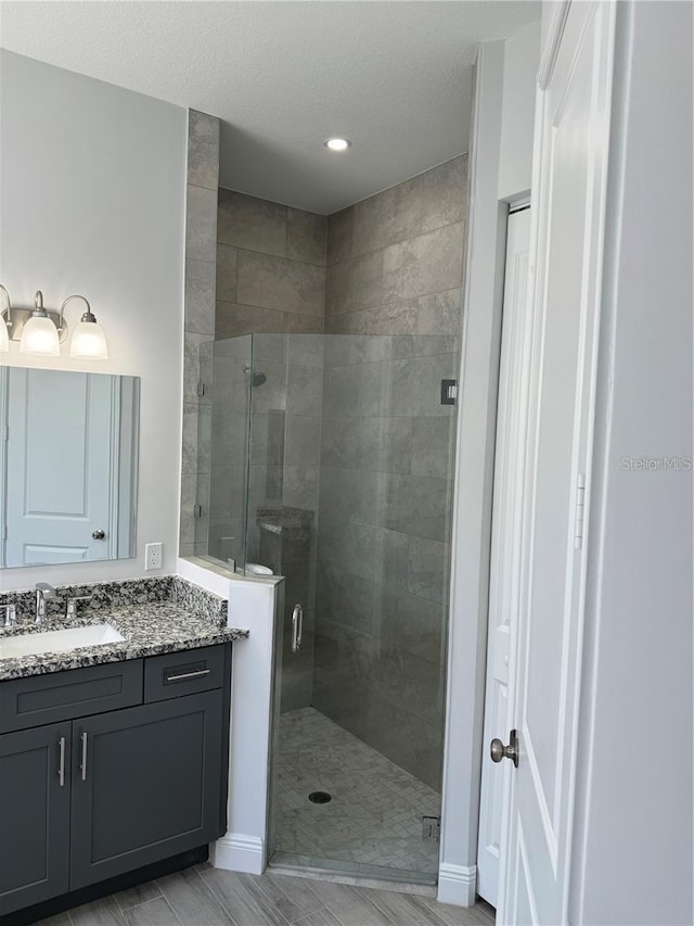 bathroom featuring vanity, walk in shower, and a textured ceiling