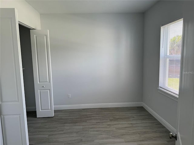 spare room with dark wood-type flooring and plenty of natural light