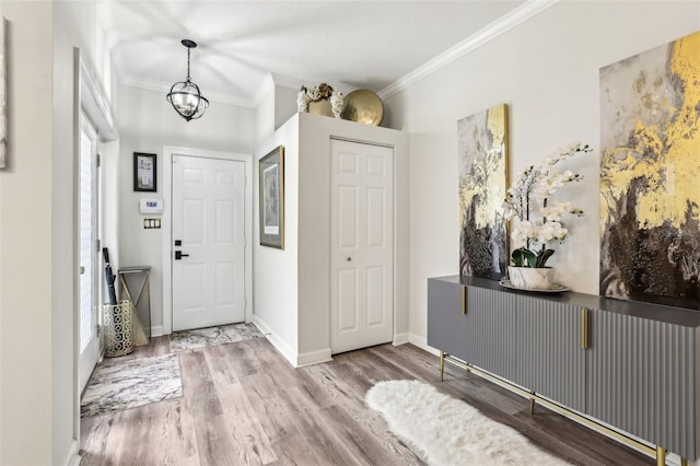 foyer with wood-type flooring, ornamental molding, and a chandelier