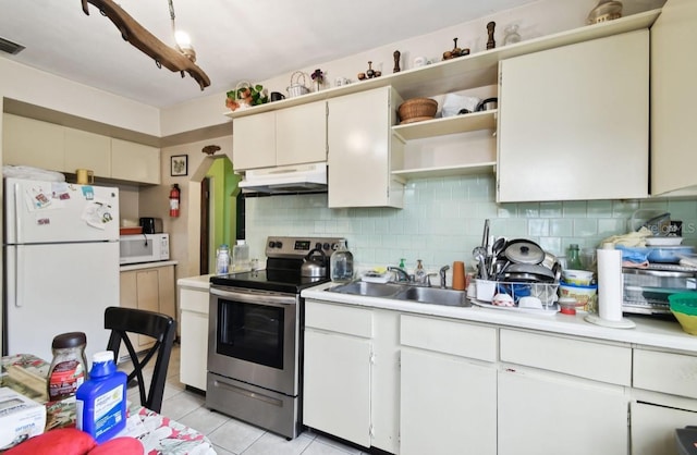 kitchen with white appliances, tasteful backsplash, white cabinetry, light tile patterned floors, and sink