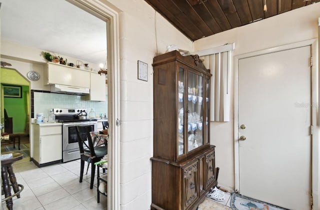 kitchen featuring wood ceiling, tasteful backsplash, stainless steel range with electric stovetop, vaulted ceiling, and light tile patterned floors