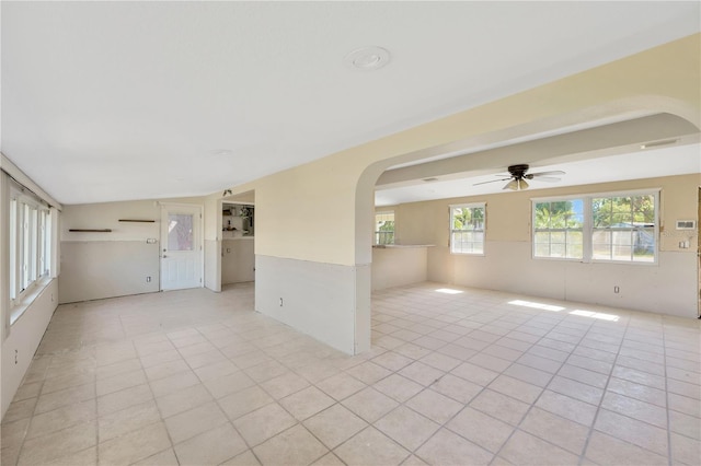 spare room featuring arched walkways, a ceiling fan, and light tile patterned floors