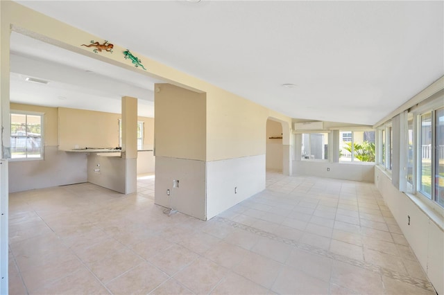 empty room with arched walkways and light tile patterned floors