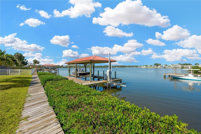 dock with boat lift, a water view, and fence