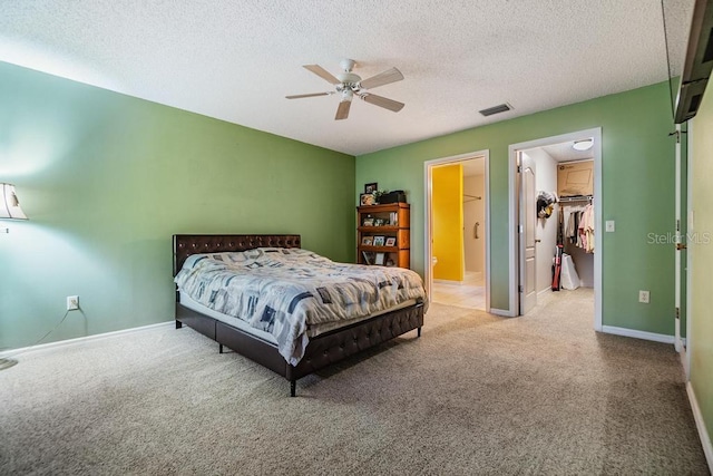 bedroom with ceiling fan, carpet floors, a textured ceiling, a spacious closet, and a closet