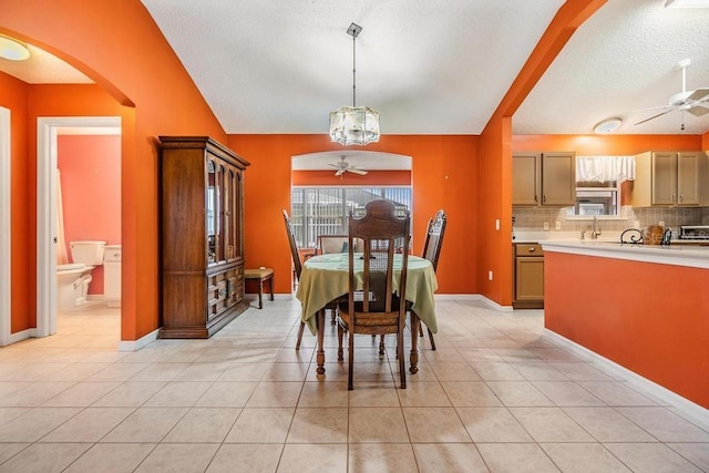 dining area with vaulted ceiling, ceiling fan with notable chandelier, and light tile patterned floors