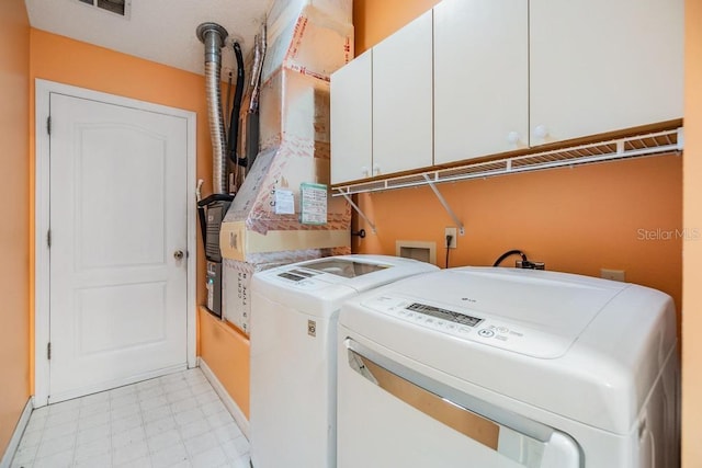 clothes washing area with cabinets and separate washer and dryer