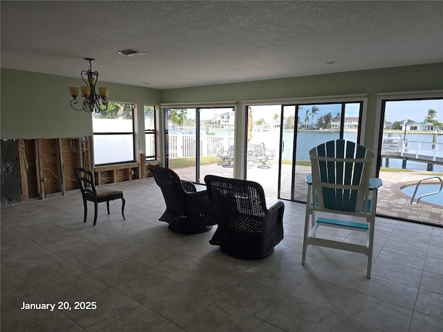 sunroom / solarium featuring a notable chandelier and a water view