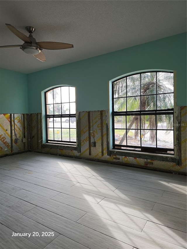 empty room with a textured ceiling and ceiling fan