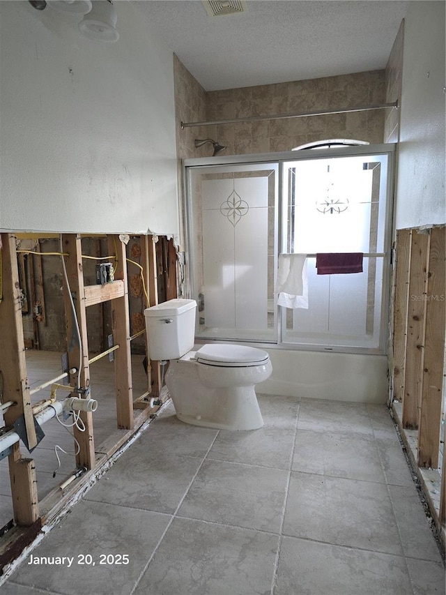 bathroom featuring toilet and bath / shower combo with glass door